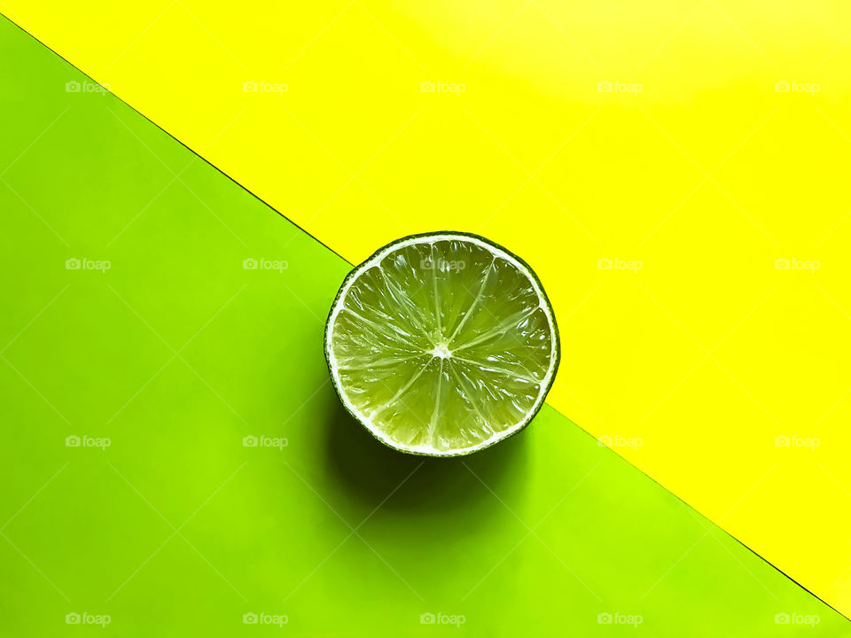 Slice of lime on green and yellow monochrome background 