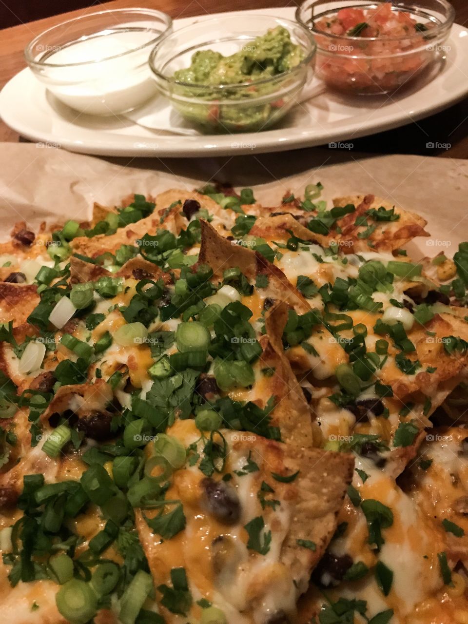 Extra cheesy Nachos, corn chips with two types of hot melted cheese, peppers, jalapeños, black olives & green onions. Served on the side with sour cream, guacamole & spicy salsa. Yummy! 🥵