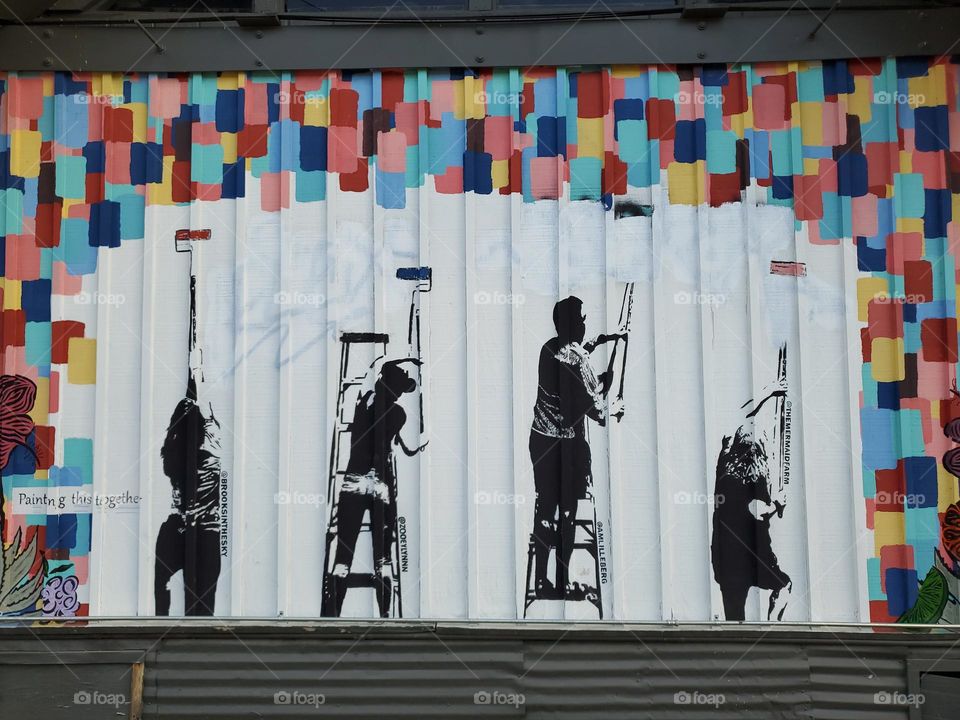 Rectangles on outdoor mural of people painting with paint rollers.