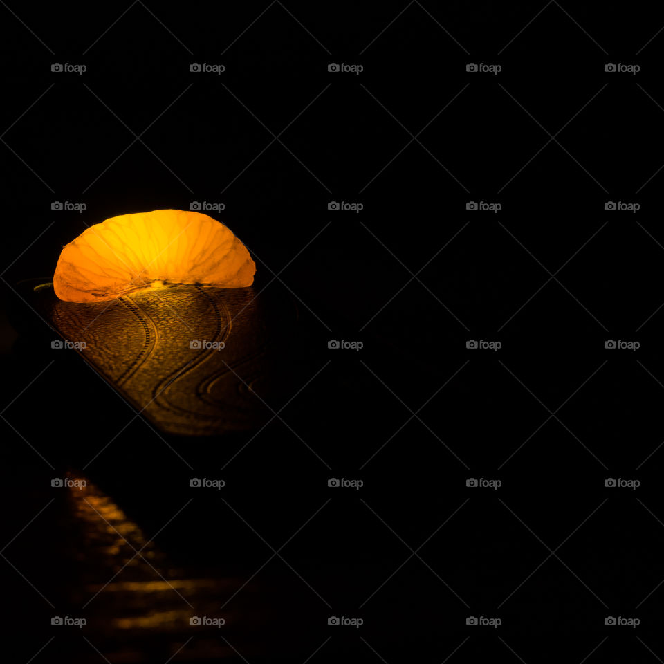 Orange fruit is photographed in artificial light.