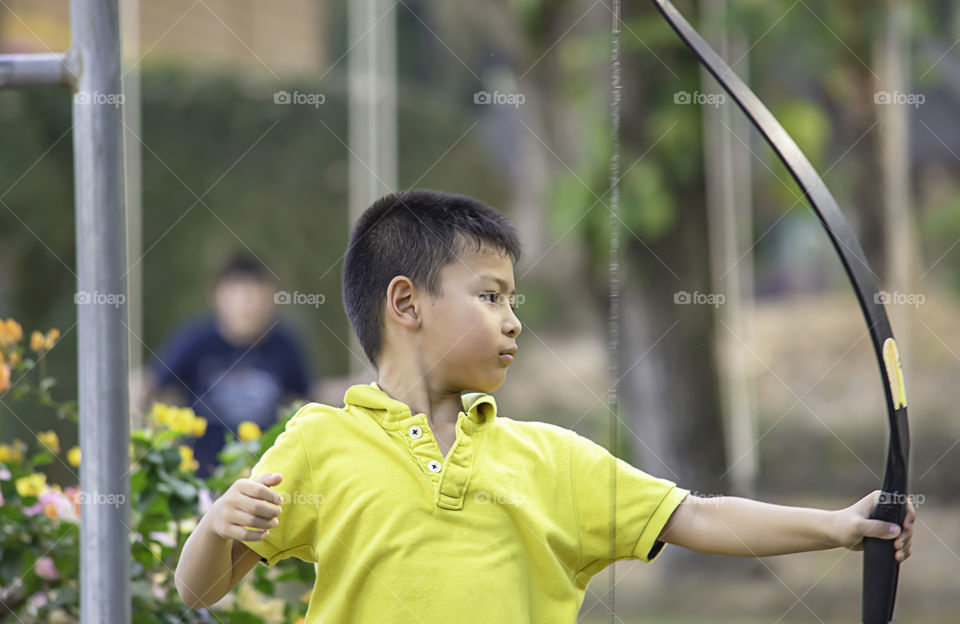 Asian boys are archery in camp adventure.