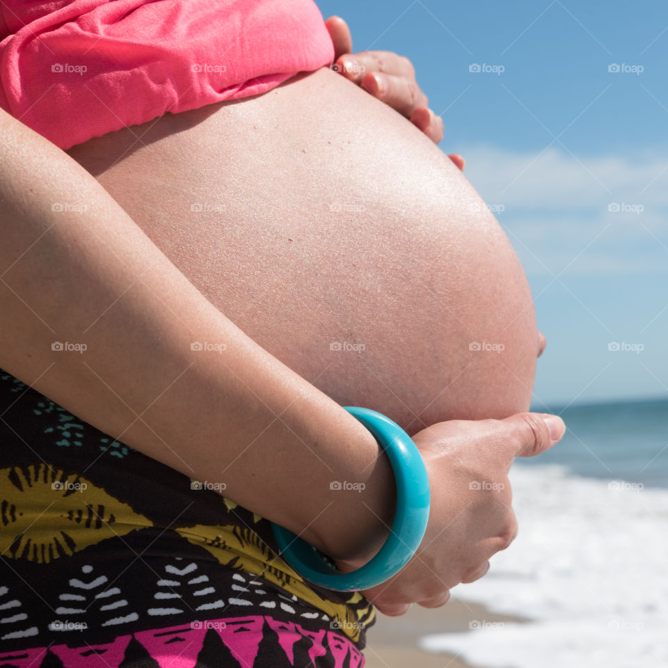 pregnant woman holds hands on belly