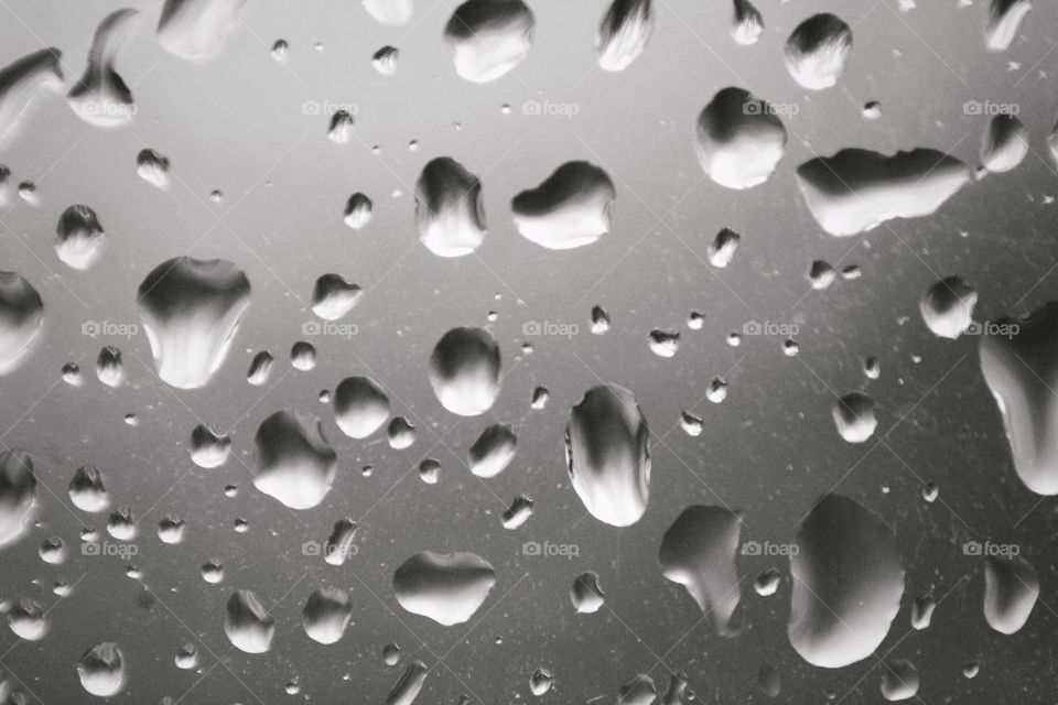 Close up of raindrops on a window in black and white. Moody and sad atmosphere.