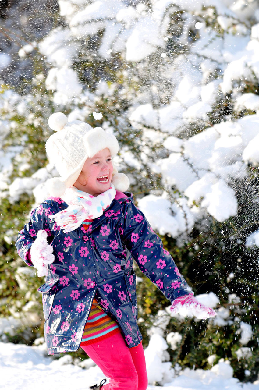 A YOUNG WHITE GIRL, AGED SIX, HAS FUN PLAYING IN THE SNOW.