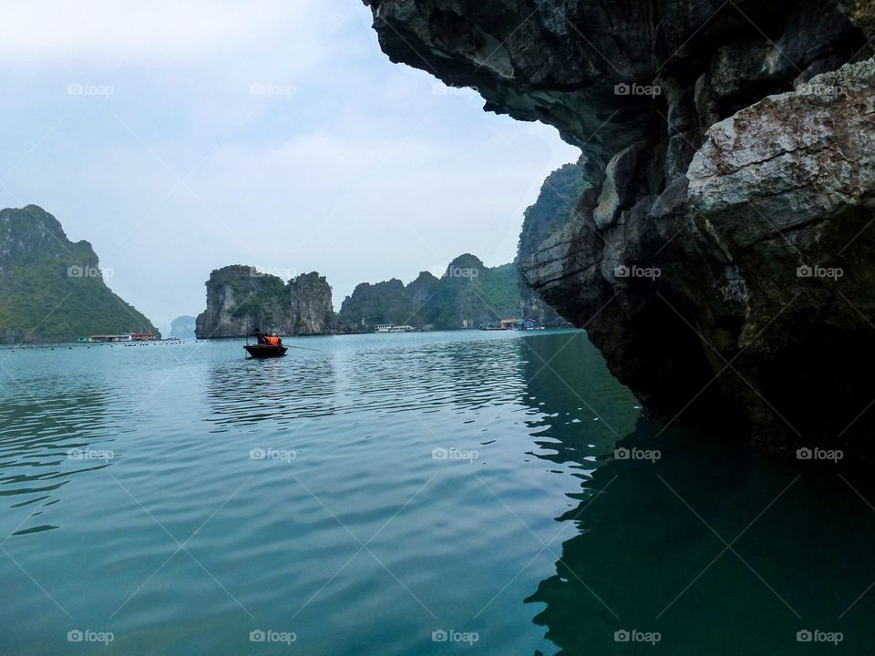 row a boat in the bay, amidst blue water and lots of rocky mountains, blue sky and cloudy, little sunshine . The air is a bit cold, the scenery is great