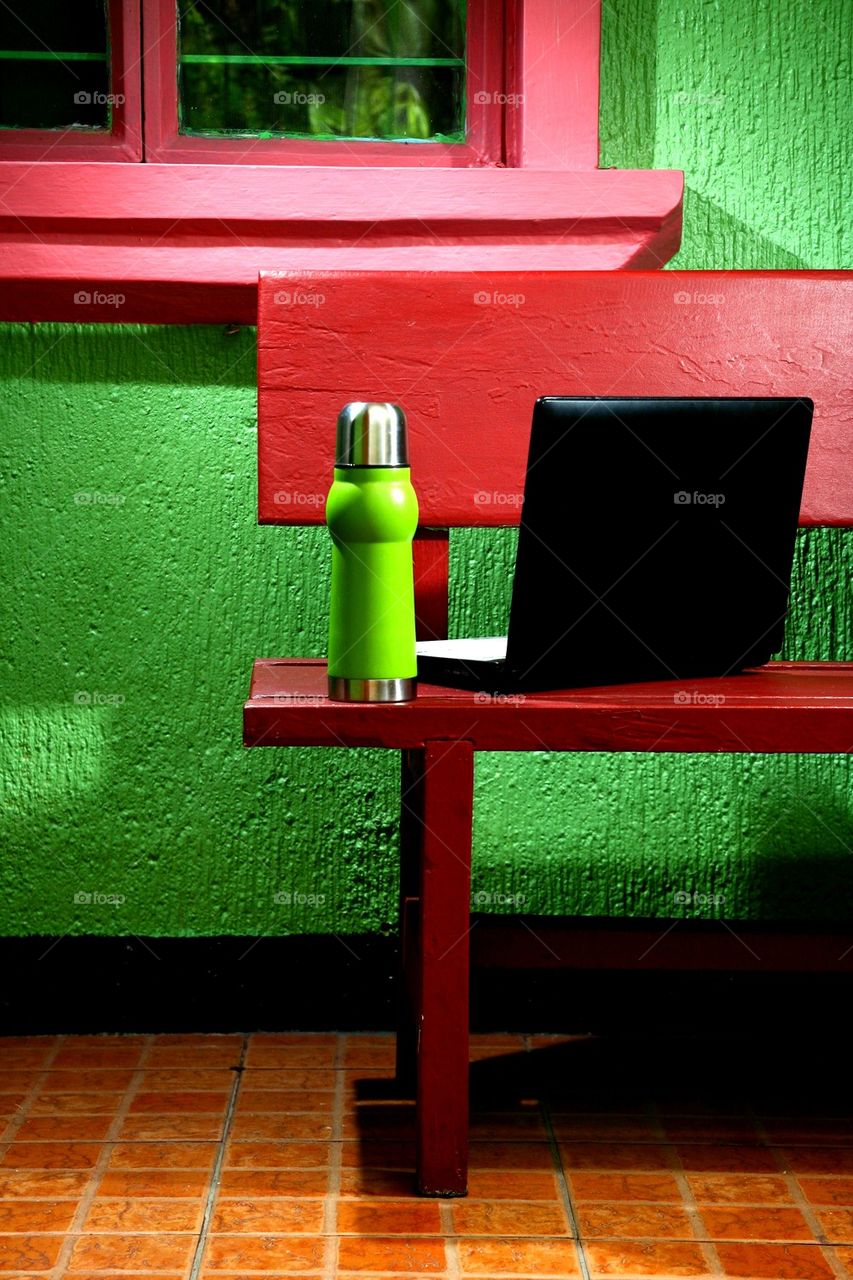 flask and laptop computer on an outdoor bench