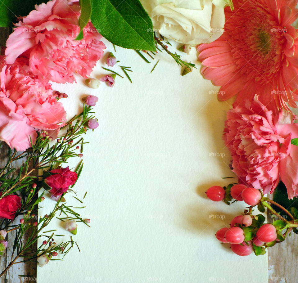 Spring, flowers, floral border, flower border, flat lay, white paper, wooden background, pink flowers and leaves, carnations, portrait orientation