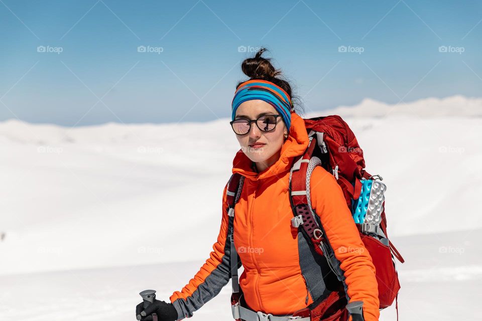 Young millennial woman, hiking in the mountains, during wintertime.
