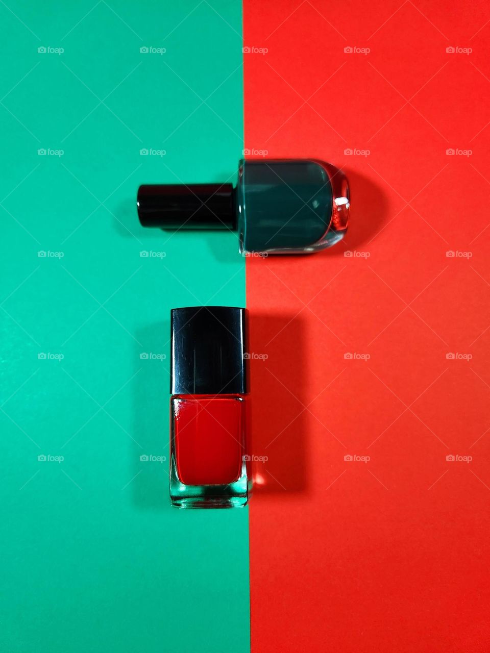 Red and green complementary colours flatlay composed with nail varnishes placed on coloured papers