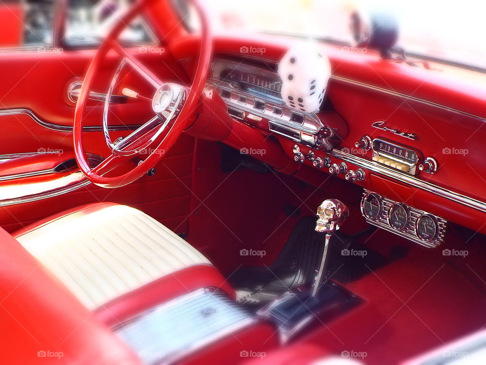 Red and white interior of classic car with fuzzy dice
