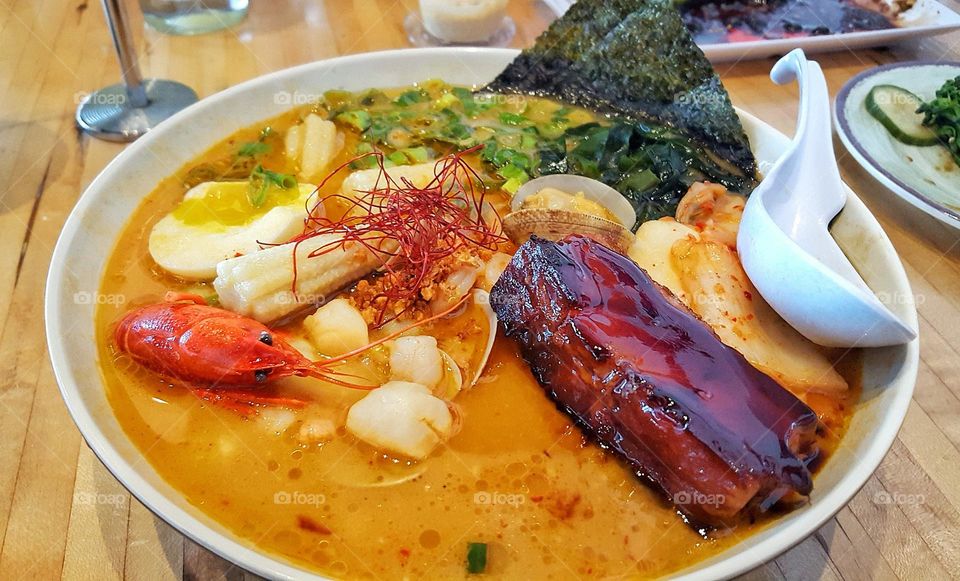 Spicy seafood ramen noodle soup with pork belly and vegetables