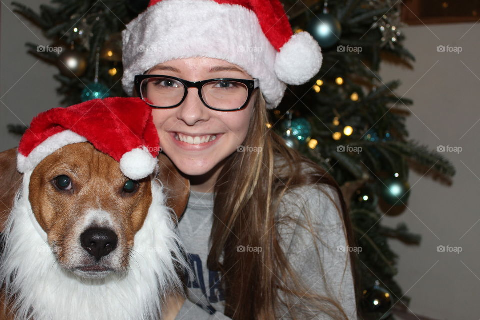 Woman and dog wearing Santa's hat