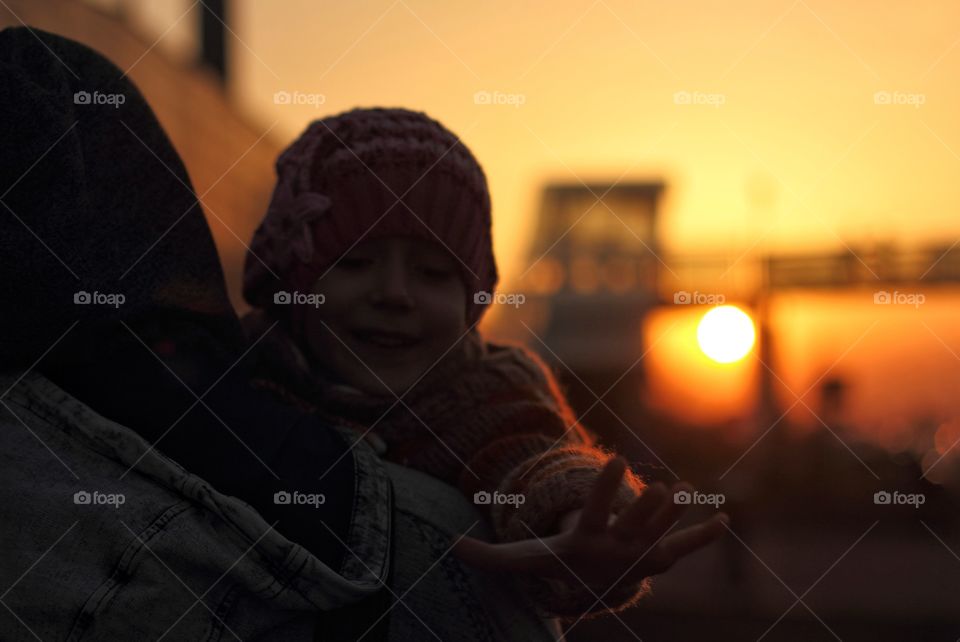 Dad carries daughter ea hands in the sunset
