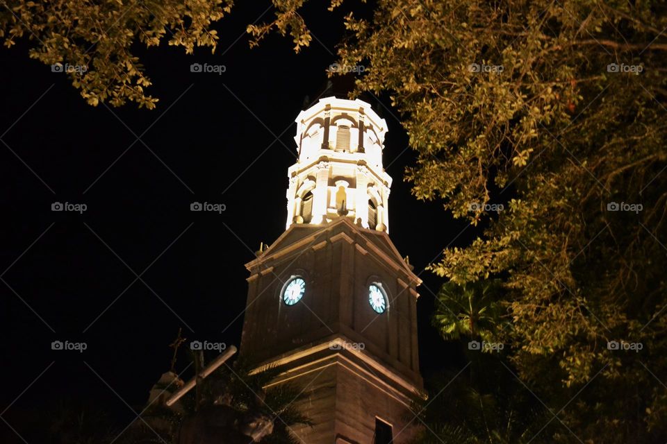 An ornate, lighted turret framed by golden leaves against a black night sky