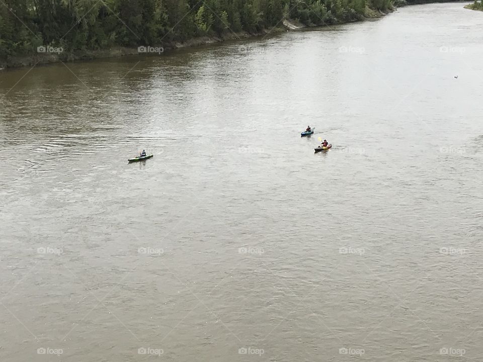 Three people kayaking in the river.