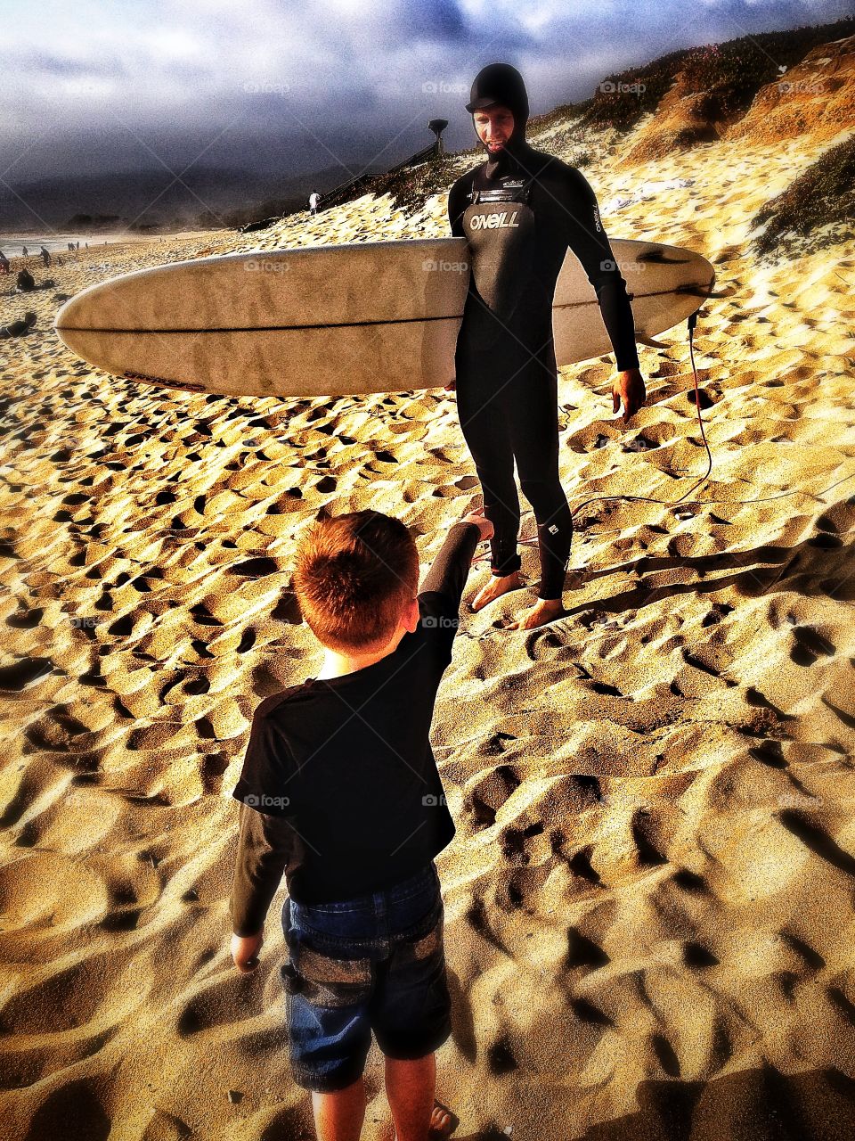 Surfer In The Golden Hour. Young Boy with His Surfer Friend On A Beach Before Sunset
