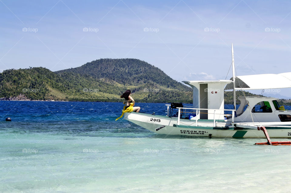Girl in bikini in a boat, sunbathing in the summer sun, in paradise island
