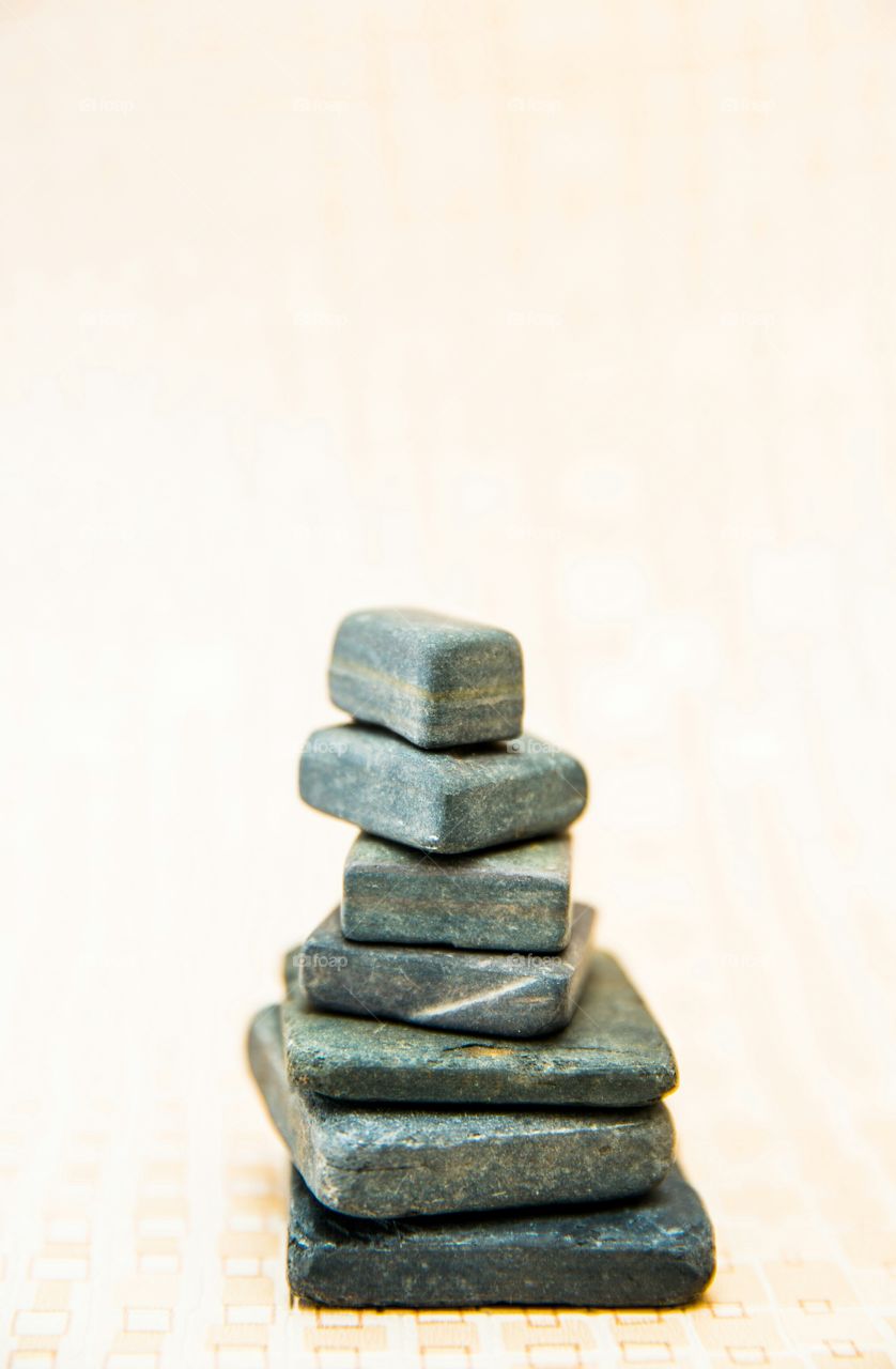 Stack of square and rectangle shaped slate pebbles on light square textured background