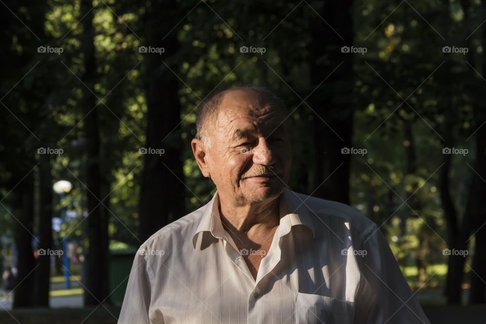 Portrait of an elderly man in a white shirt, smiling to a new day.