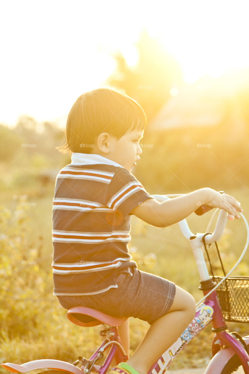 Young boy riding his bicycle. during golden hour on a summertime