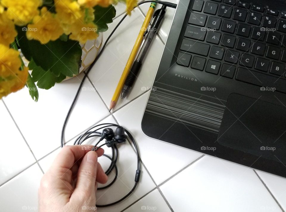 Hand holdung earphones connected to a laptop computer