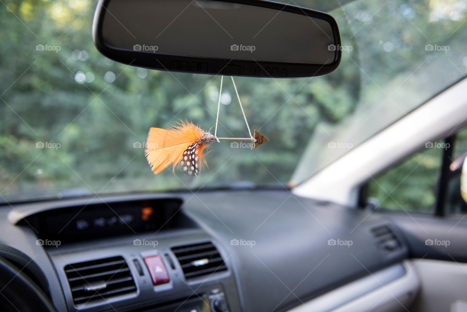 Handmade arrow with feathers hanging from the rearview mirror of a car