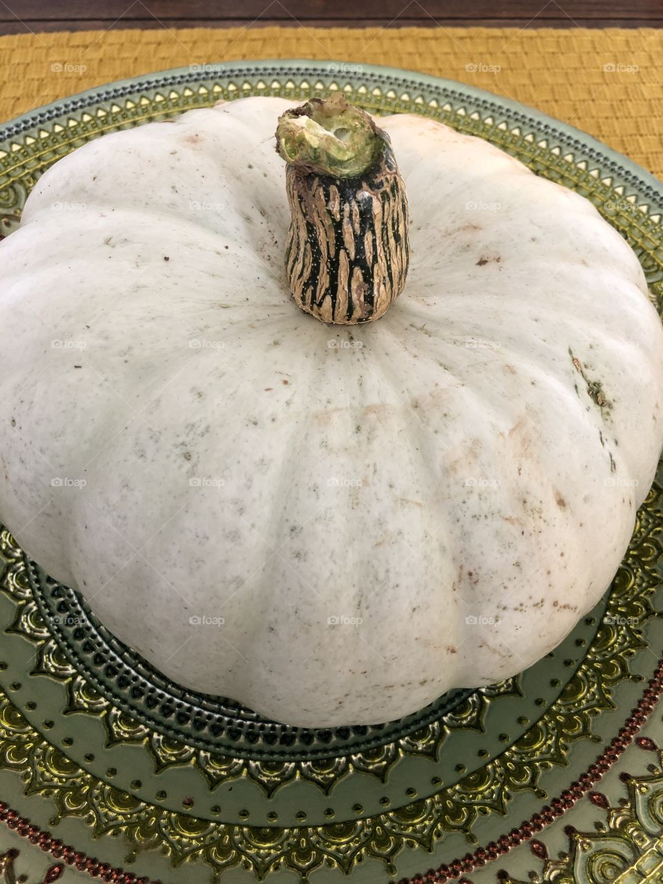 White pumpkin sitting in green fruit bowl 