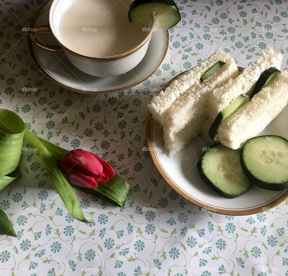 A healthy cucumber sandwich for a tea time brunch displayed on a floral background with a delicate pink tulip. USA, America 