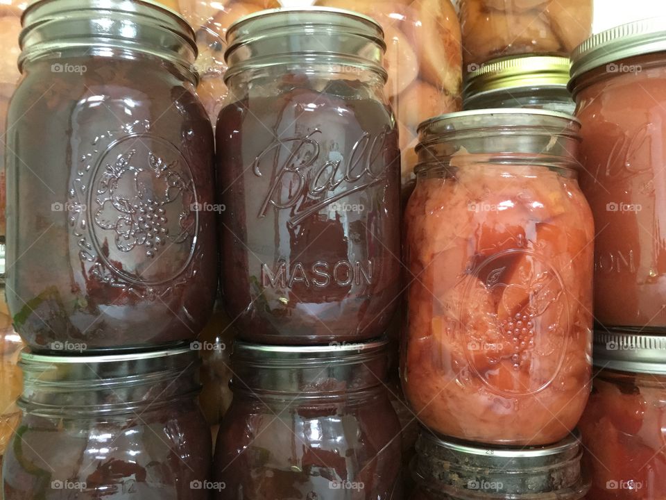Homemade fruit preserves, jams and sauces  in mason jars in cupboard pantry 