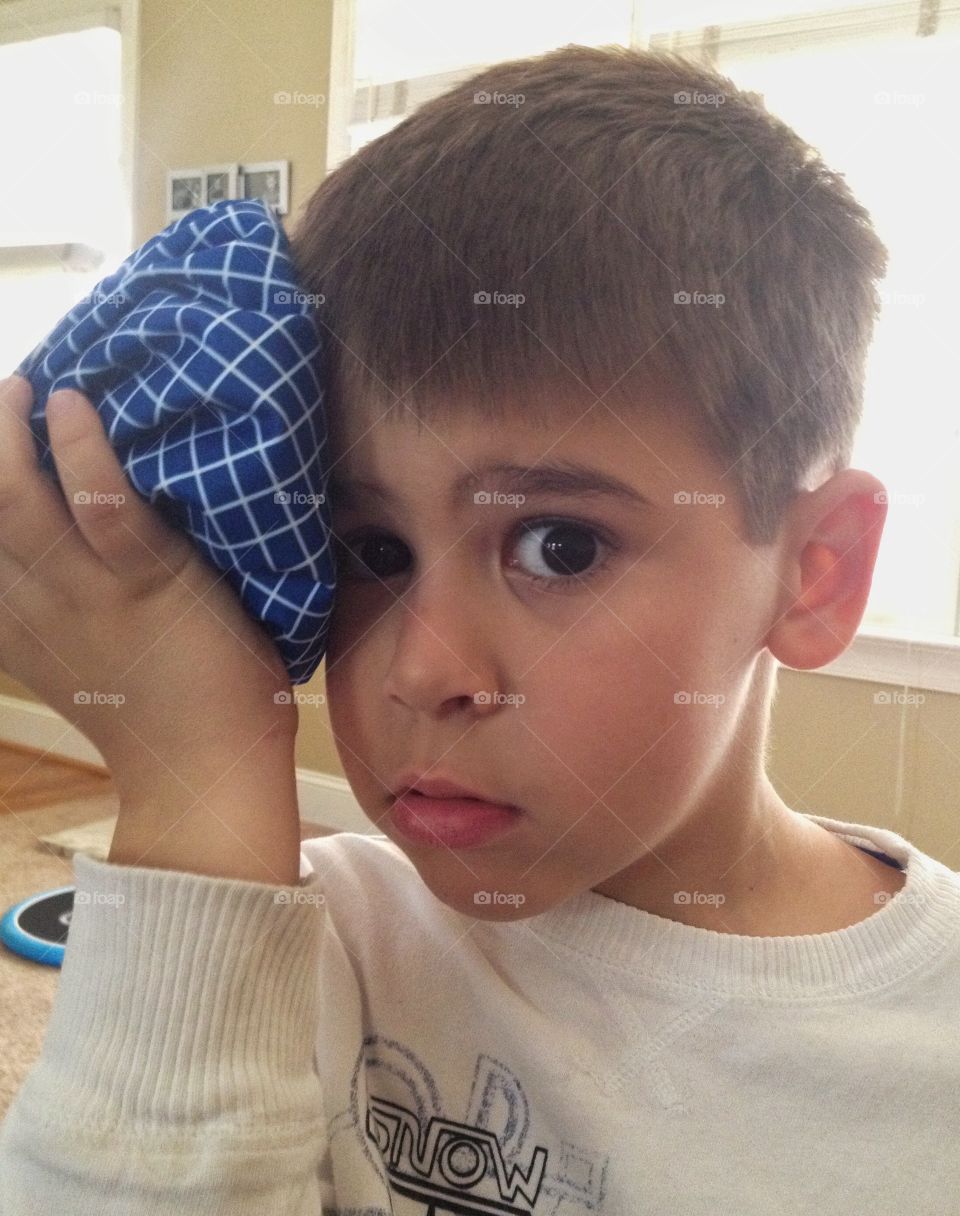 Portrait of a boy holding ice pack to his head