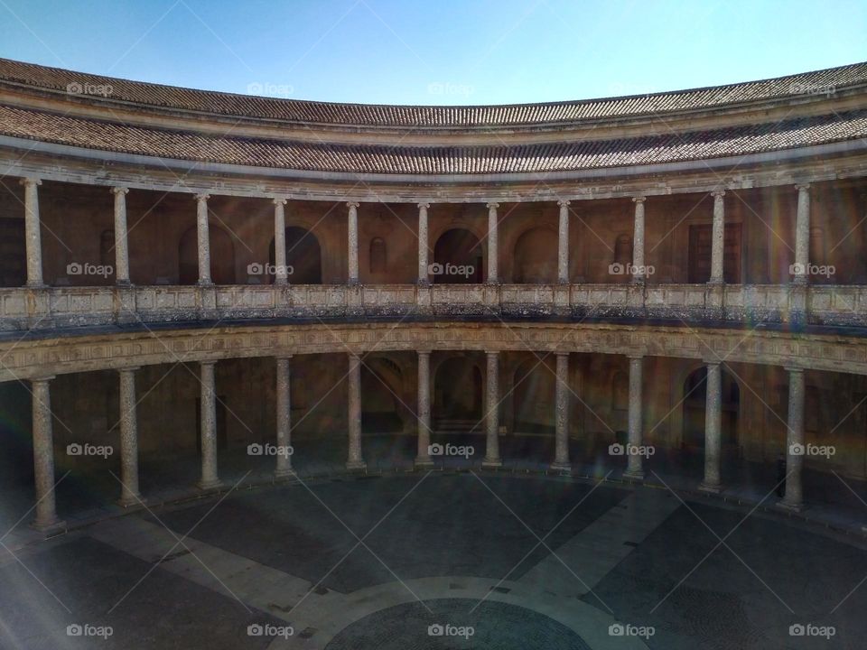 Inside the Alhambra, Granada, Spain.  A clear sky where the sun's rays can be seen playing between the architectural figures.