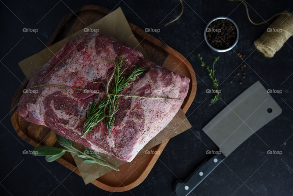 Flat lay of a pork shoulder prepped for cooking with fresh herbs and spices