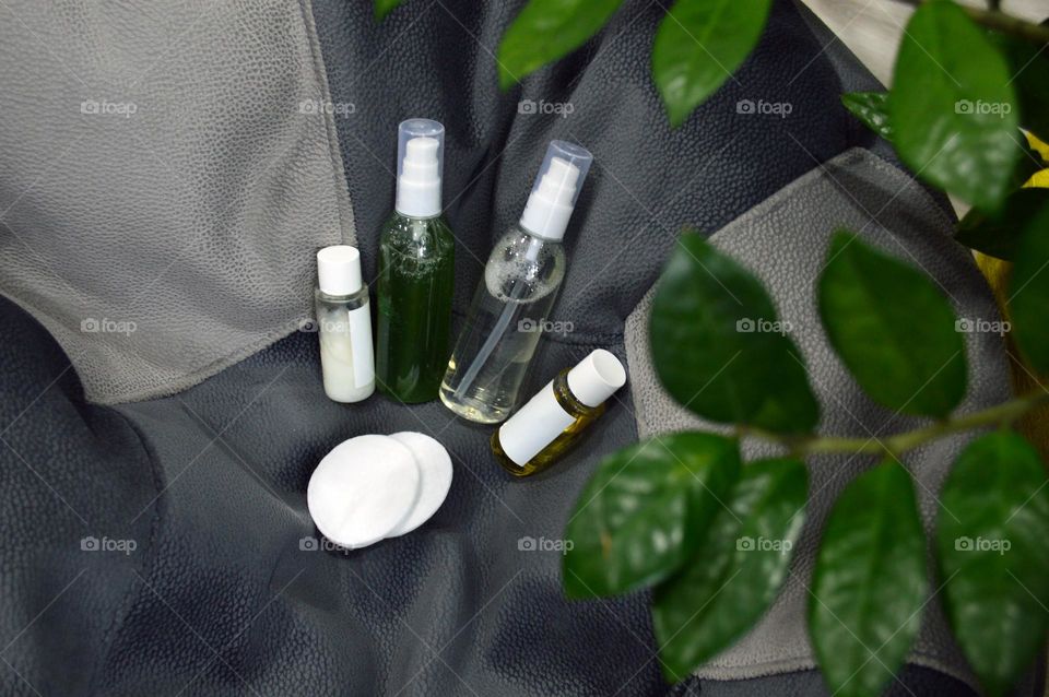 Jars with cream, shampoo and cosmetics on a background with green plants