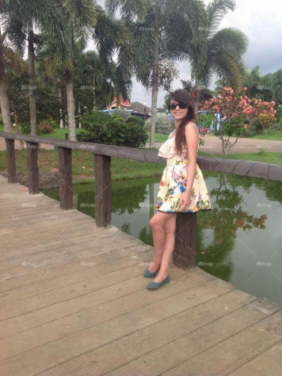 Woman standing on wooden bridge over lake with sunglasses