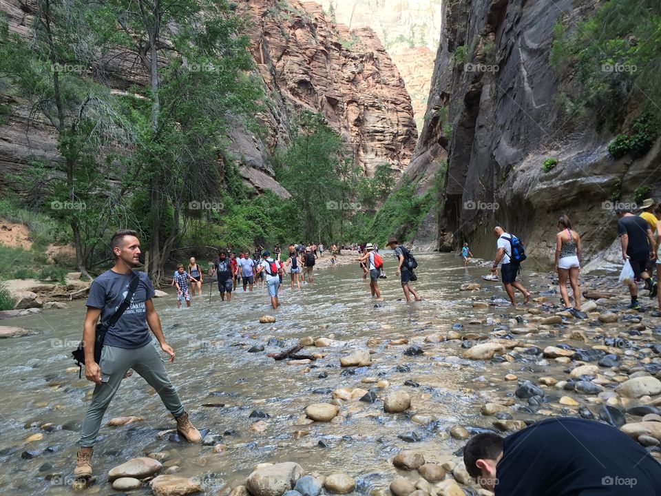 People walking in river near mountain