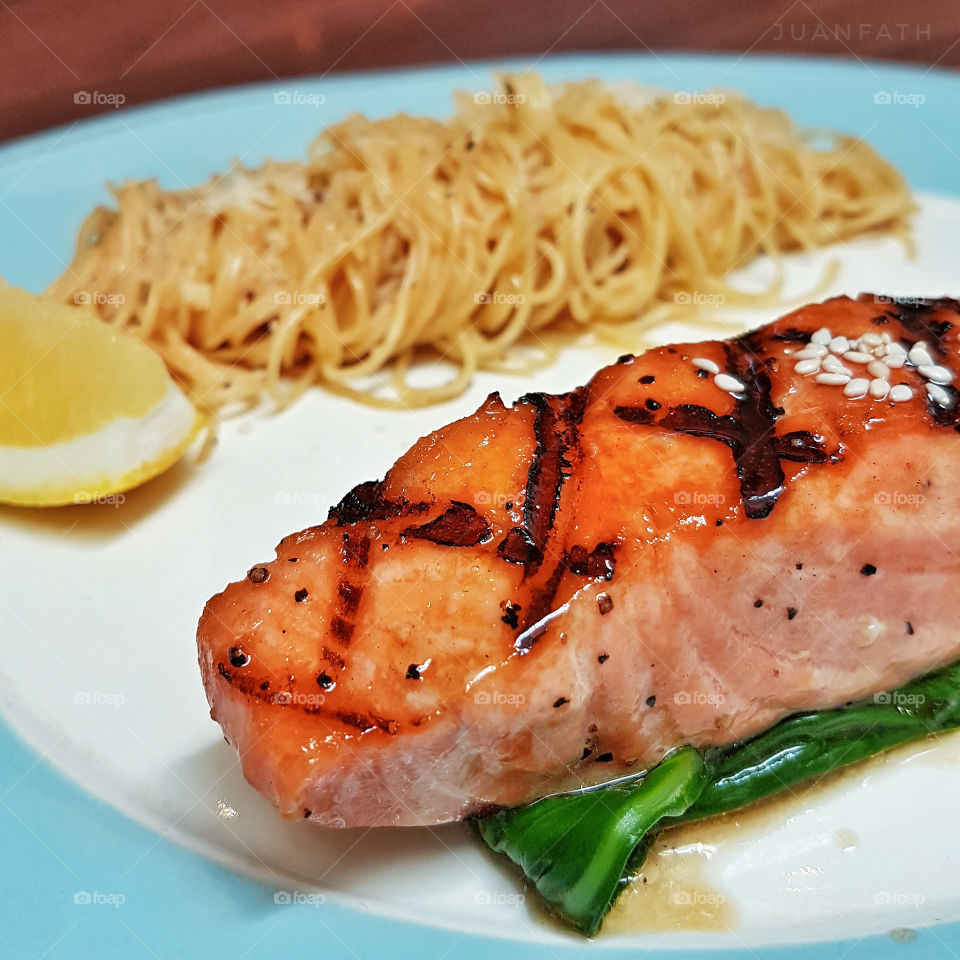 Salmon steak and noodles in plate