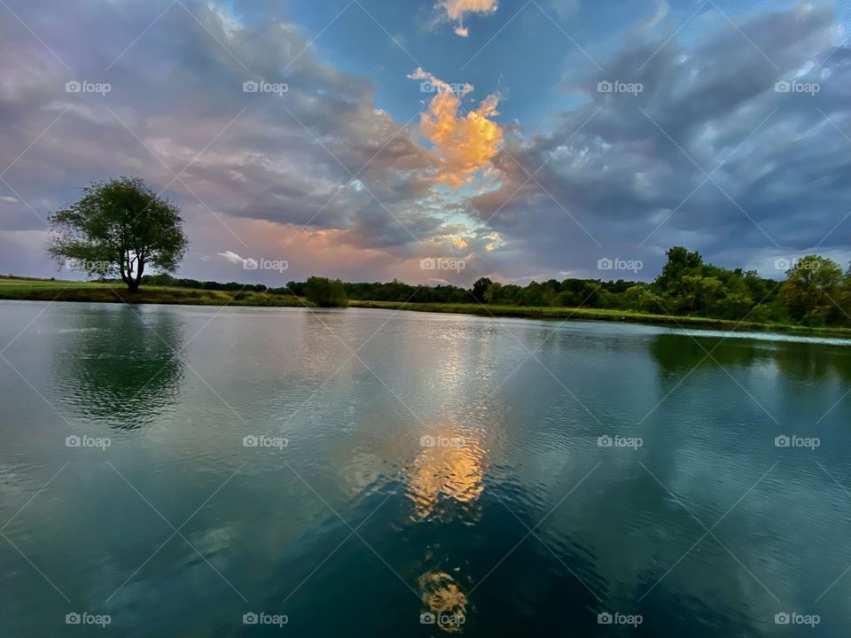 Enigmatic Prairie sunset reflecting off of a tranquil pond. With an array of unassuming, yet vivid colors.
