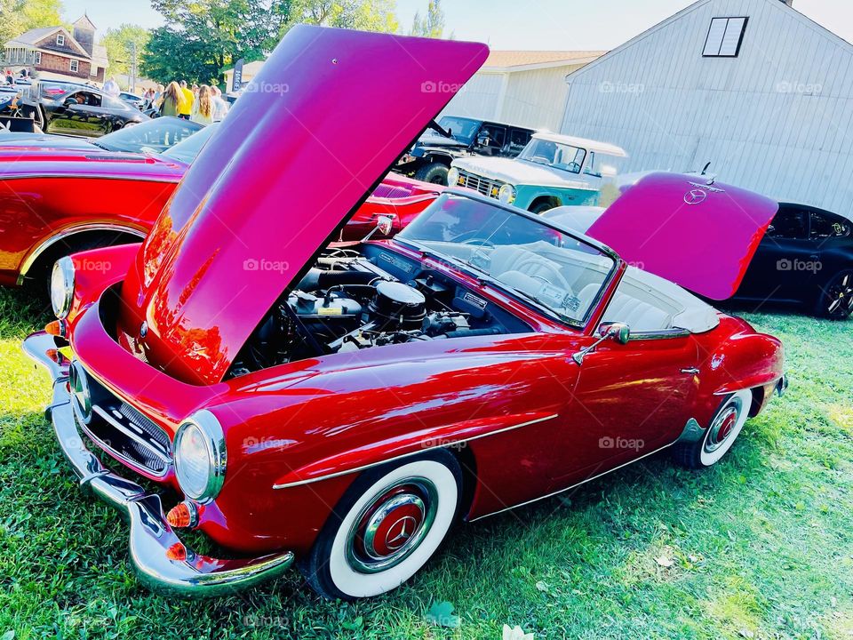 The Mercedes Benz 480SL red convertible with a glimpse under the hood. The SL class is a grand touring sports car.