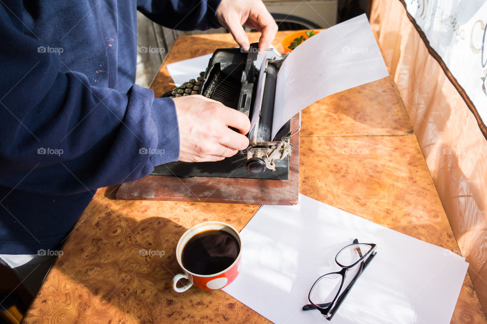 A young writer is writing his new book on his old typewriter.