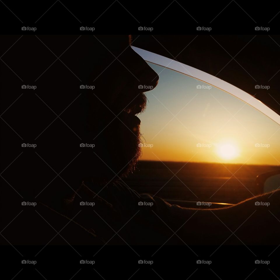 first sunrise. silhouette of a man as he drives down a highway at the first light of sunrise