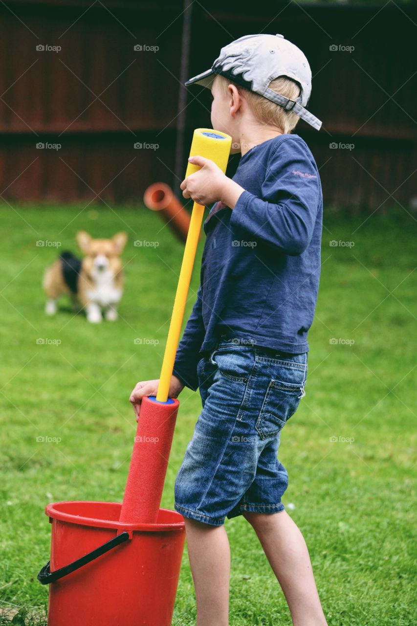 Boy play with water together with a dog kn a backyard