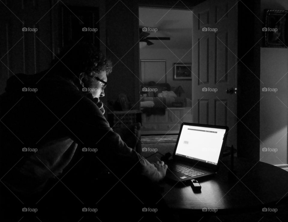 Man working on a laptop on a coffee table at home in black and white