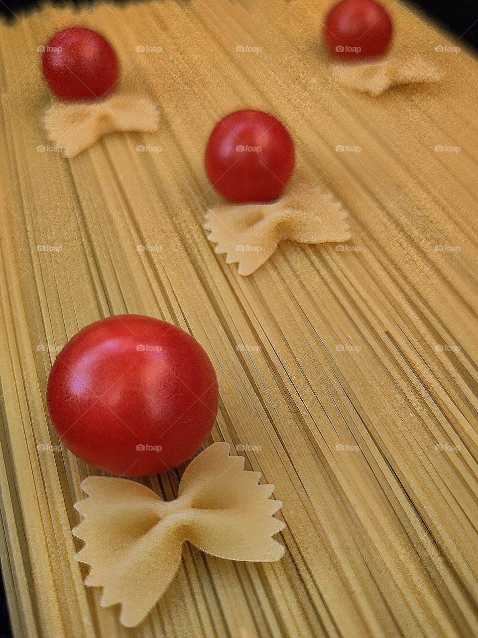 Composition. Food. "Capellini" pasta has red cherry tomatoes with "Farfalle" pasta in the shape of a bow tie