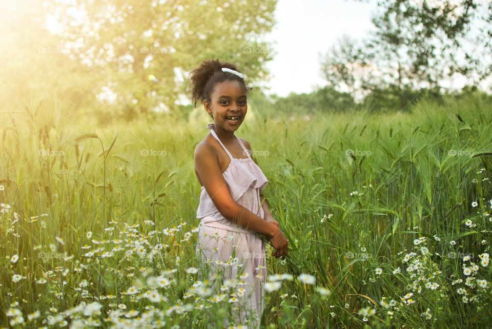 Girl walking summer field with Barlow and flowers