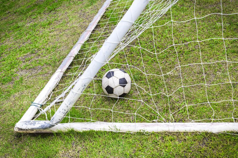 Old soccer ball in old goal net