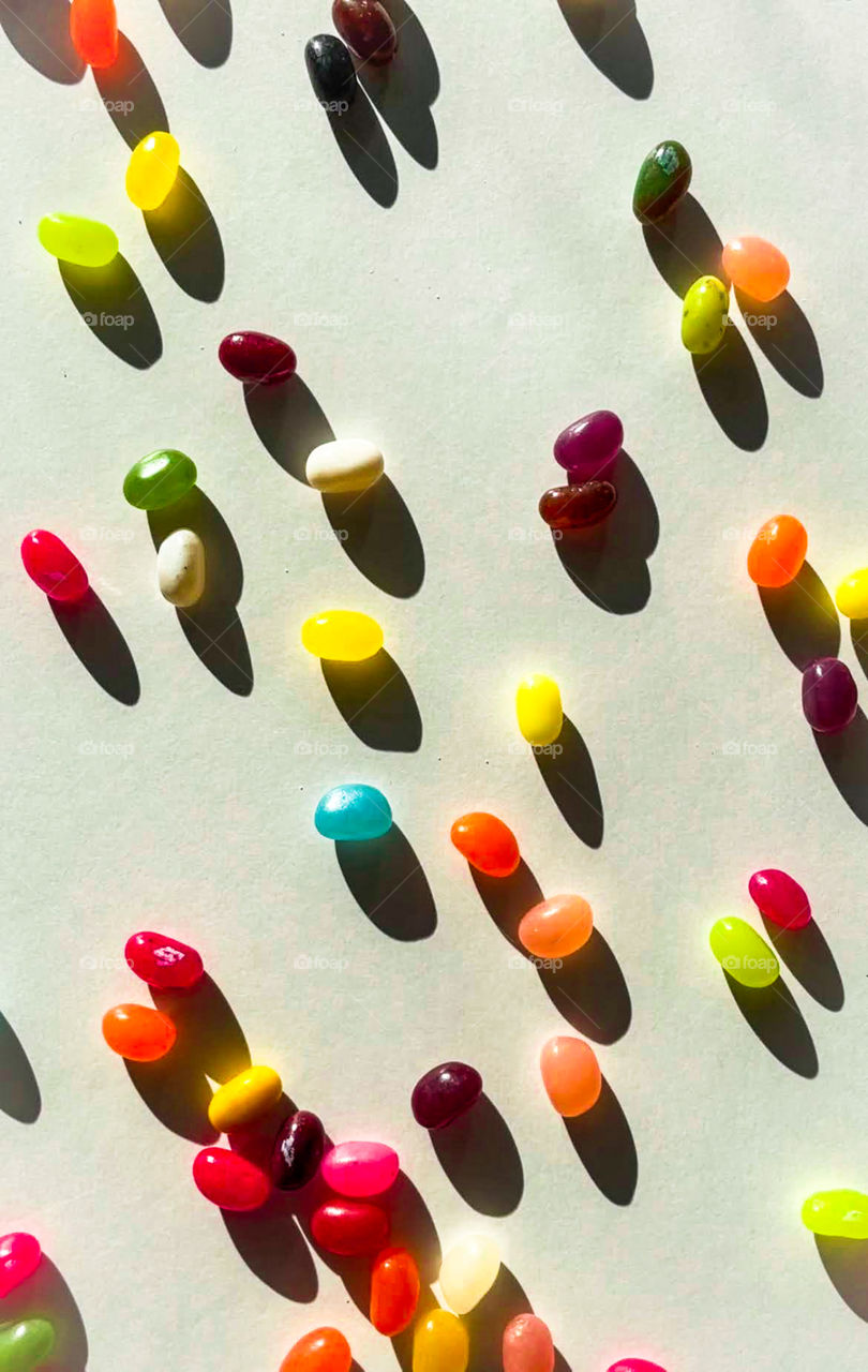 Playful, colorful jellybeans in the sun casting shadows. 