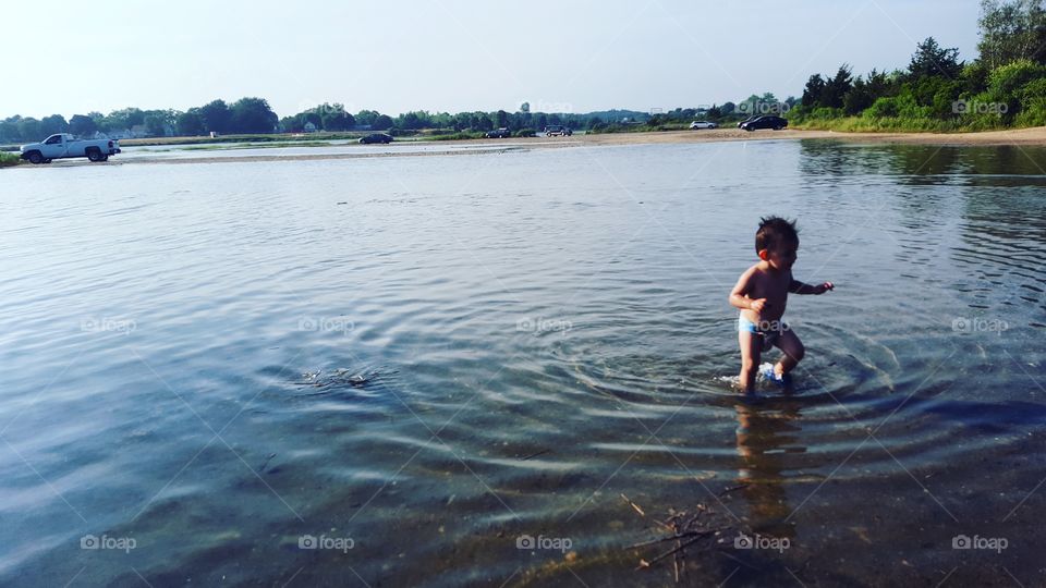 Little shirtless boy walking in lake
