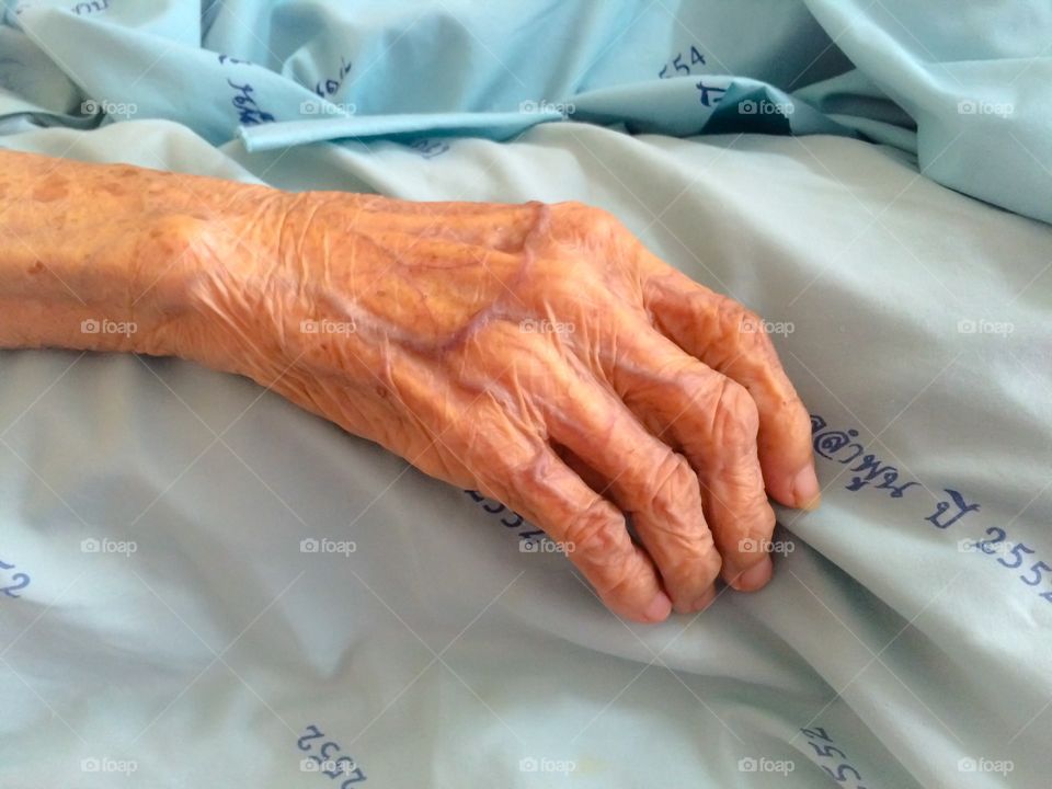 Close up aging woman hand on bed in hospital 