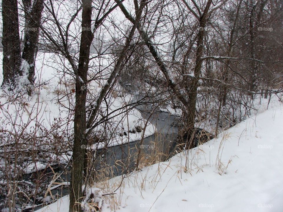 A snowy creek winding through the landscape in winter 