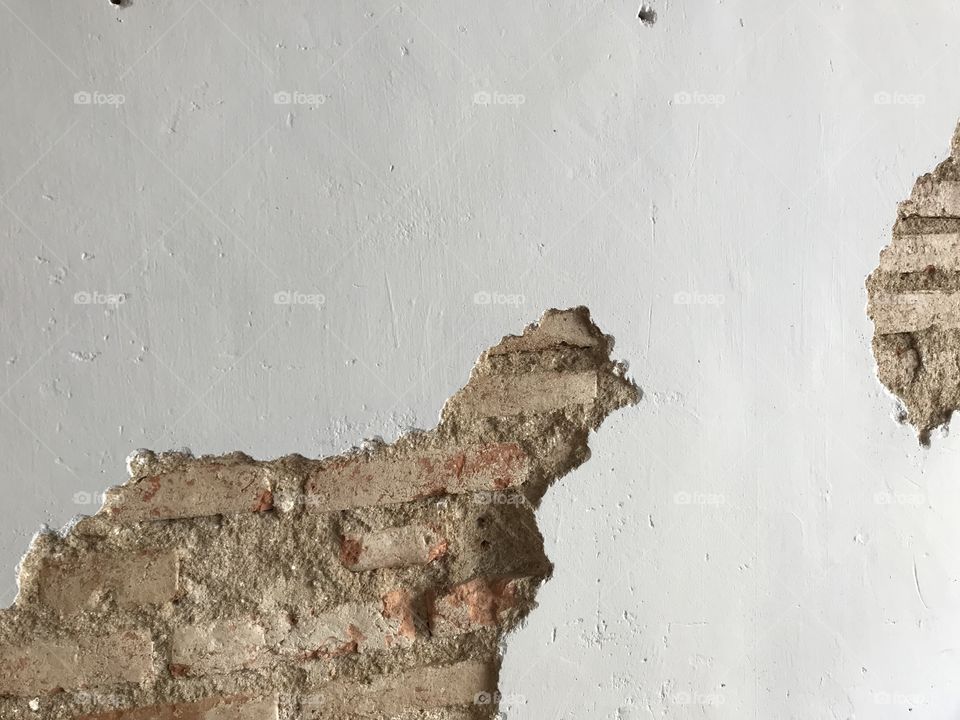 designed antique white cement wall with cracked space which shows old bricks inside, using as background